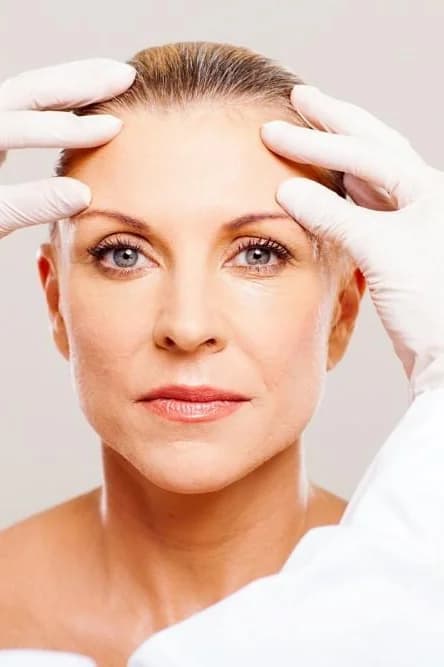 Gloved provider assessing a patient's brow before a neuromodulator treatment