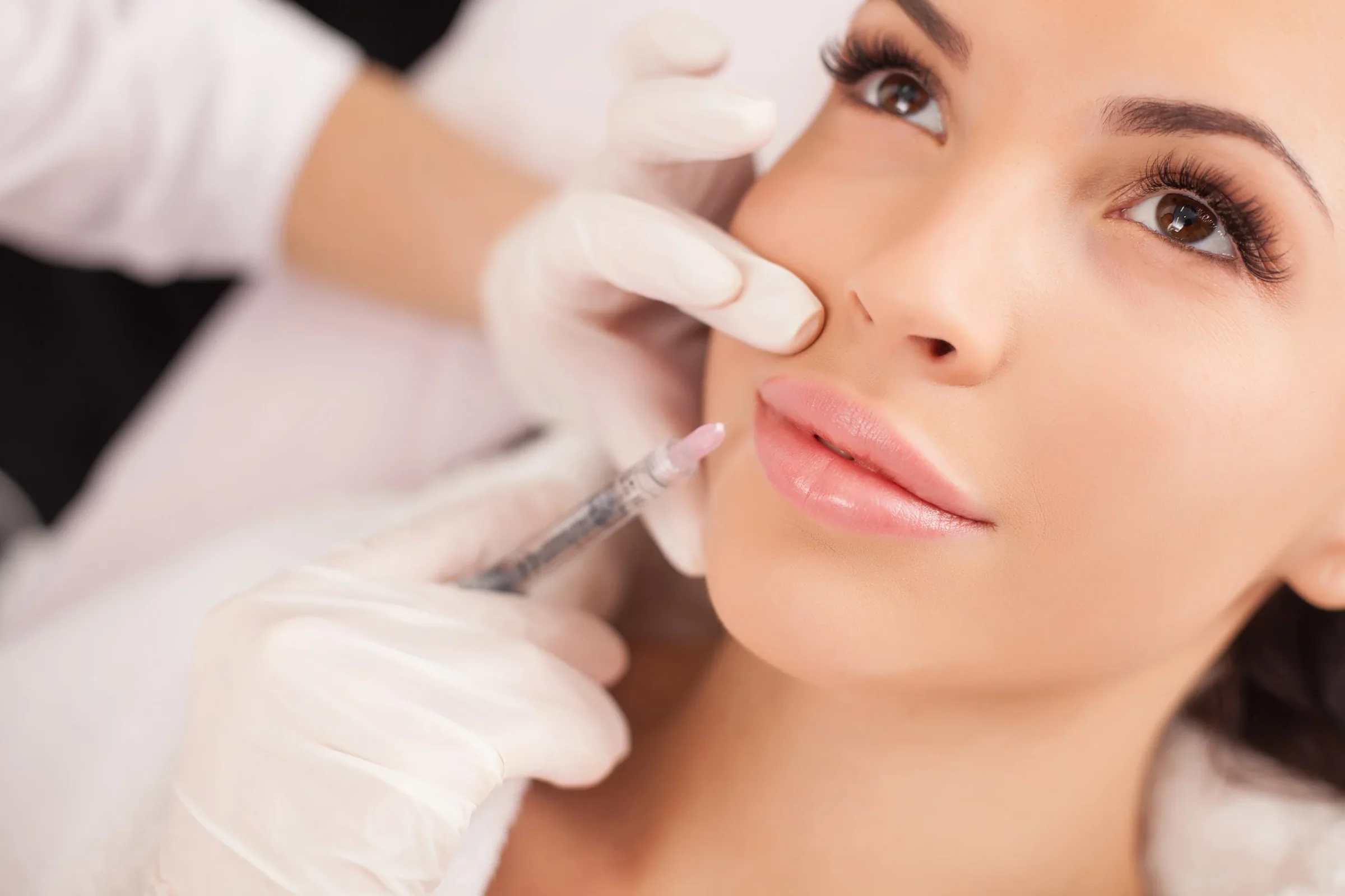 A woman receiving a facial injectable from a gloved provider